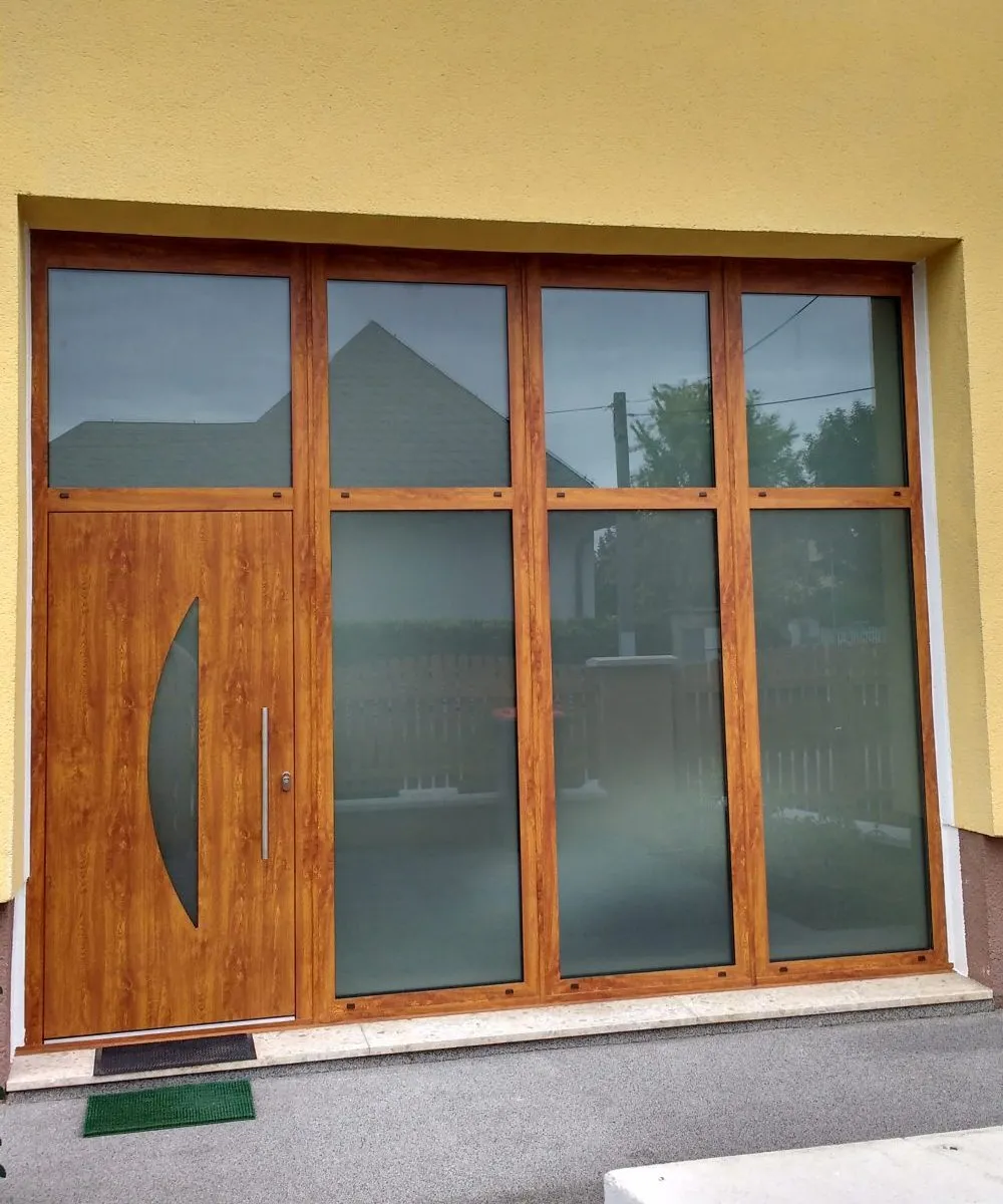 Haustür in Eichenoptik mit sichelförmigem Glasausschnitt, umgeben von großen Glasfeldern