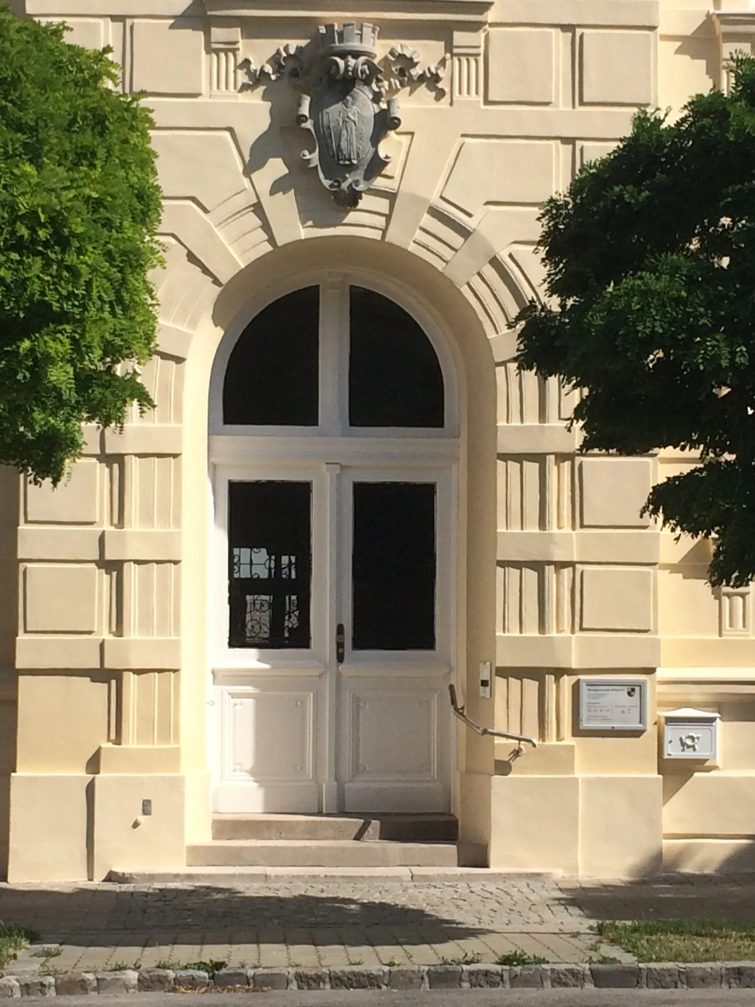 Weiß lackierte Rundbogentür in einer historischen Fassade mit Wappenstein