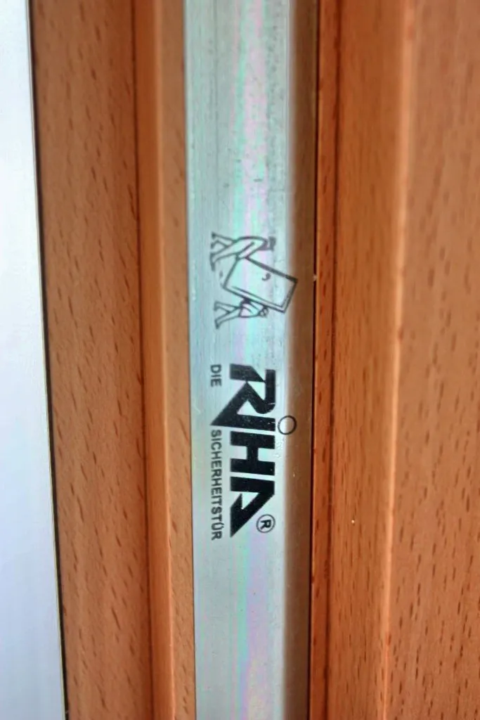 Metallleiste mit aufgedrucktem RIHA-Logo zwischen zwei Holzflächen