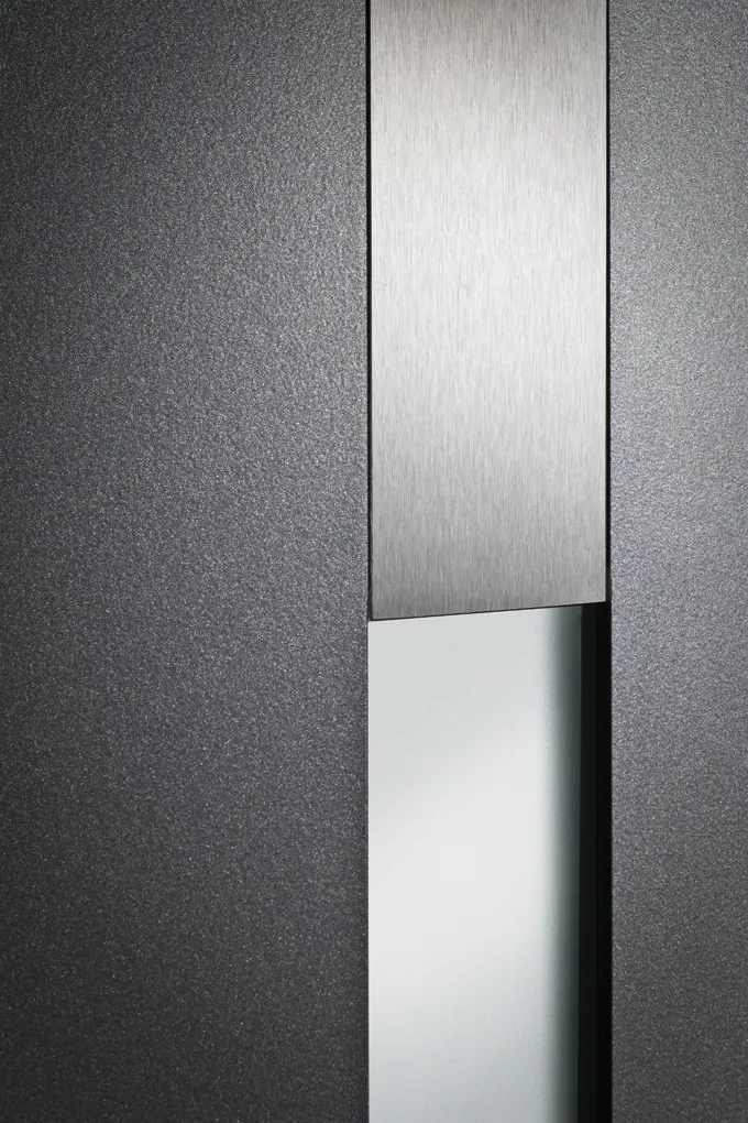 Anthrazitfarbene Türoberfläche mit senkrechter Metalleinlage und Glasstreifen