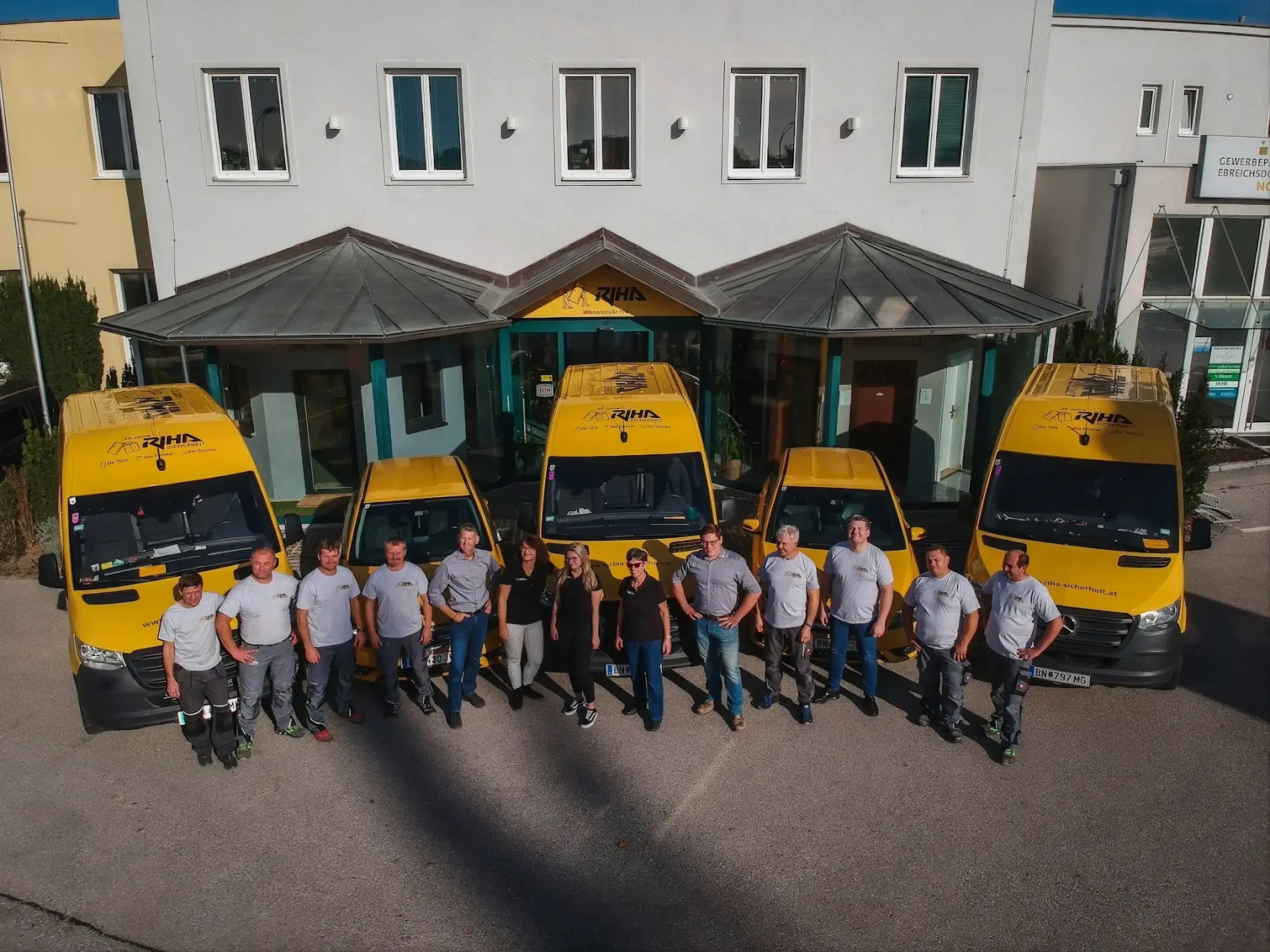 Das Team der RIHA Ges.m.b.H. vor dem Firmensitz in Ebreichsdorf mit den gelben RIHA-Montagefahrzeugen